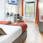 Chambre Supérieure Quadruple de l’Hôtel des Roys à Versailles – espace lumineux avec lit double, canapé et coin bureau
